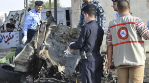قوات الأمن تفحص سيارة فجرت في الناصرية.